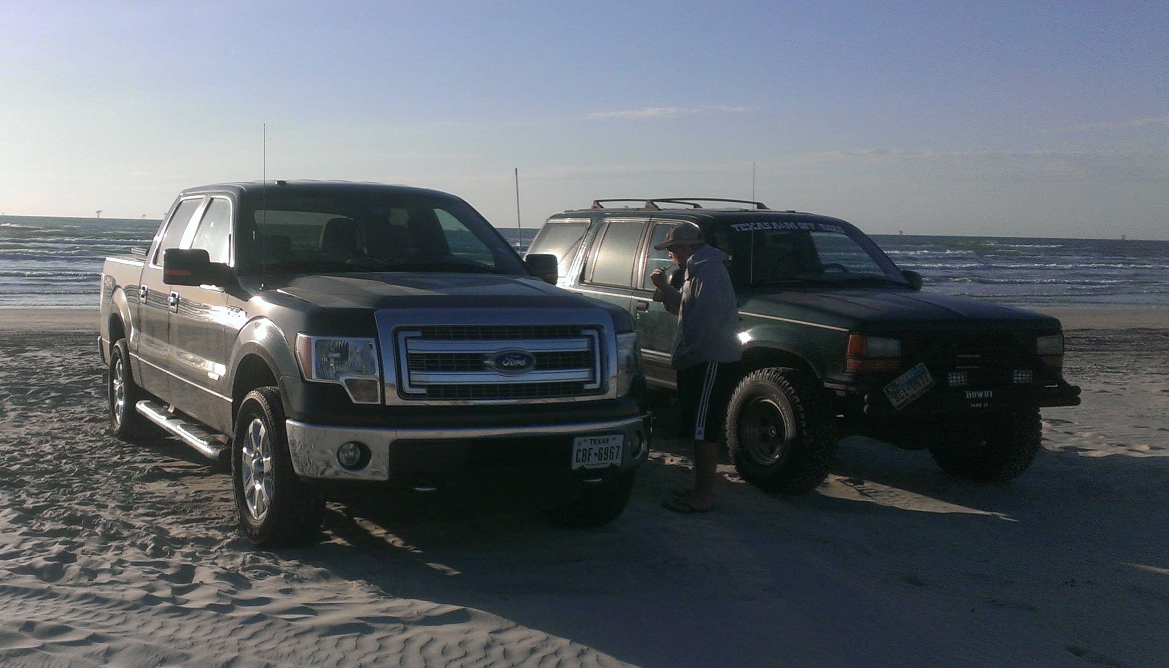 A 2014 Ford F-150 on the beach backed up towards the waterline next to the exploder, Texas A&M offroad club edition.